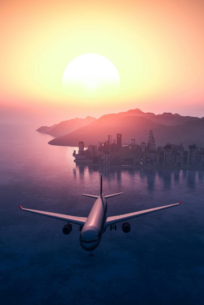 Airplane flying over the ocean towards an island city during a vibrant sunrise.